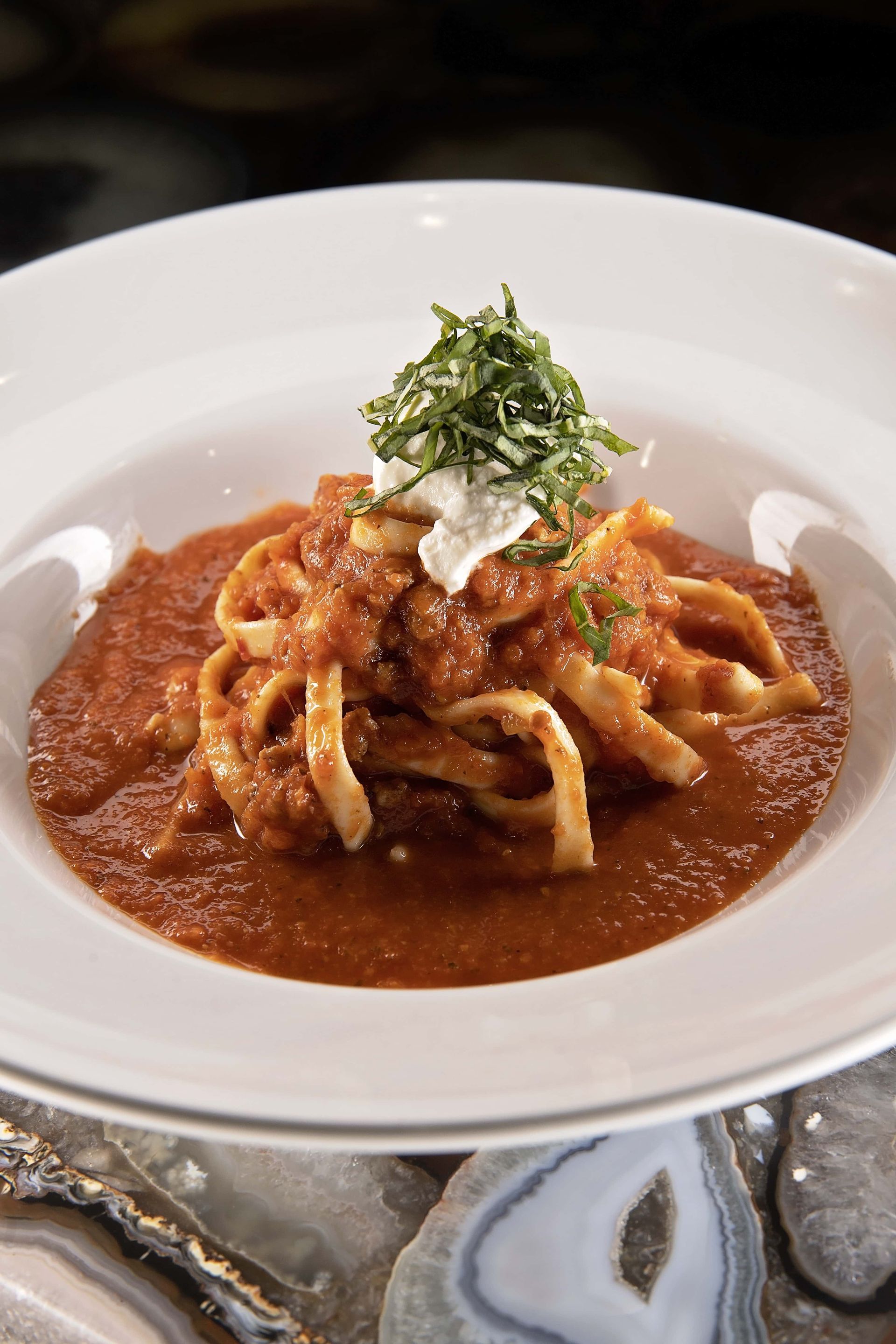 A white plate topped with noodles and tomato sauce.