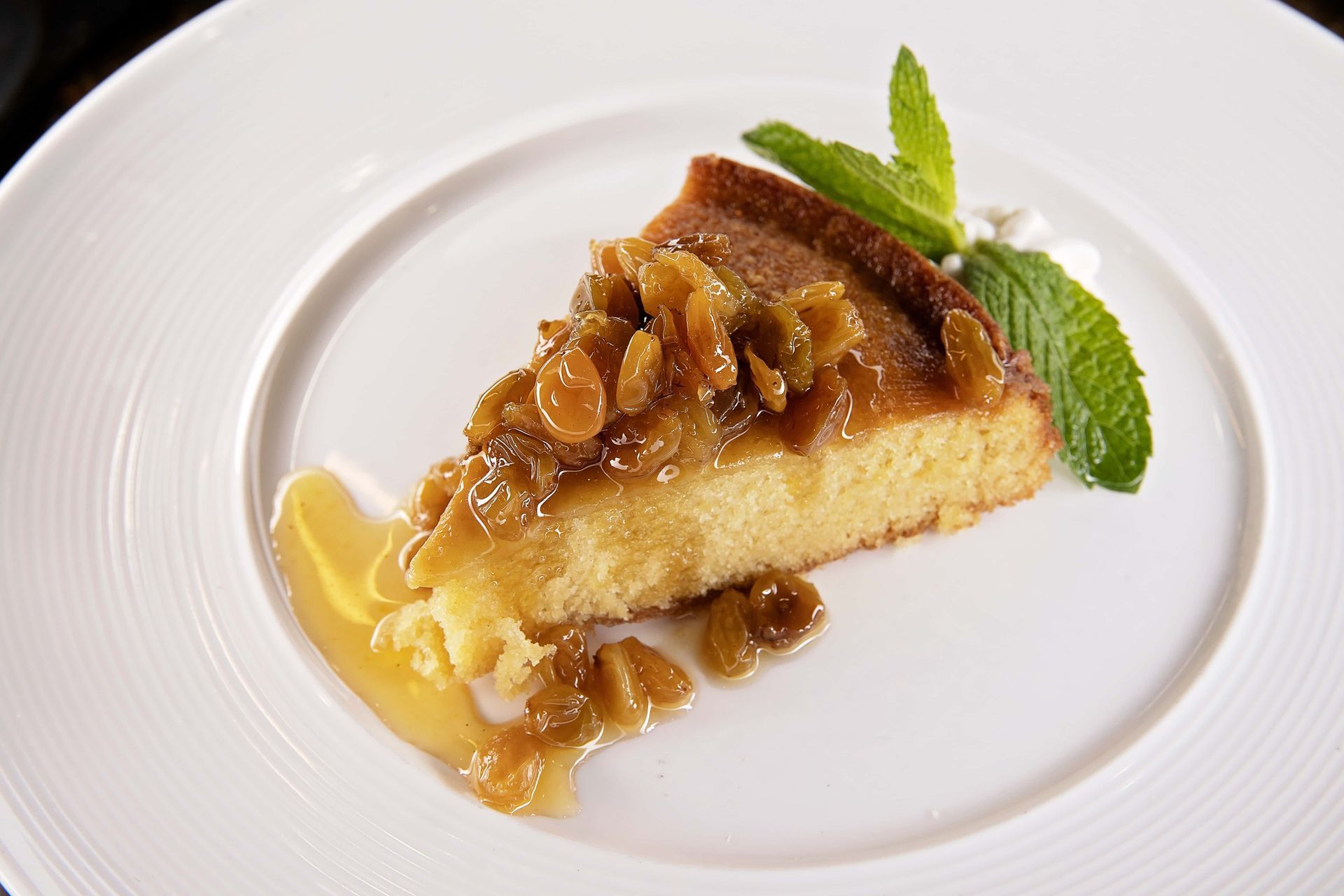 A slice of cake on a white plate with mint leaves