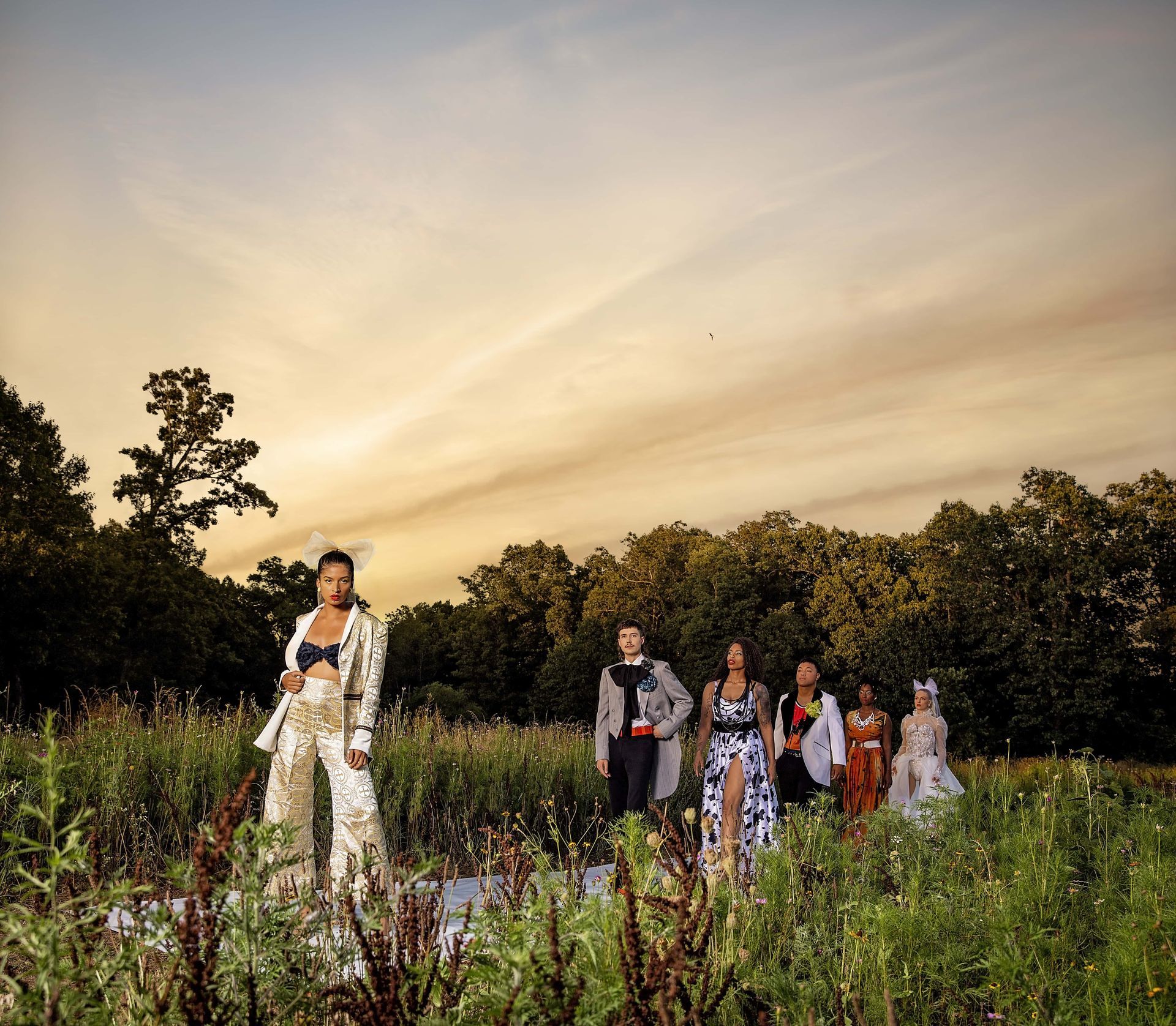 A group of people are standing in a field at sunset.