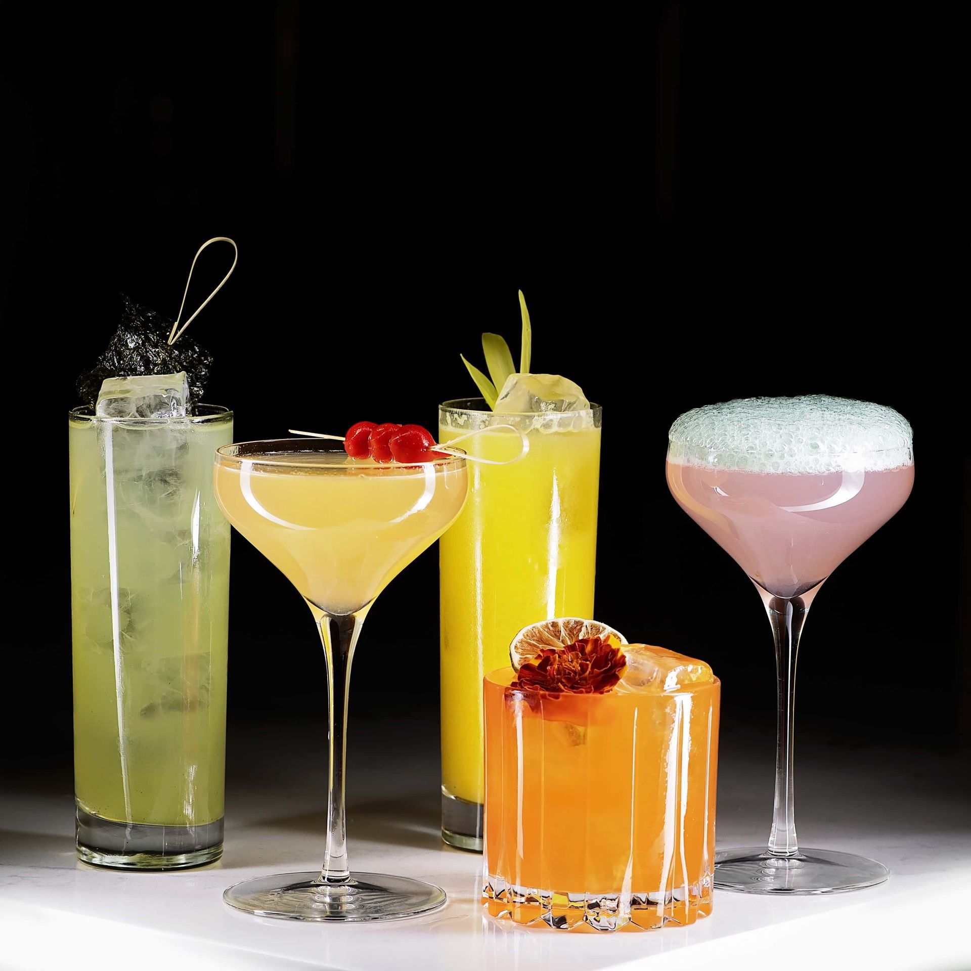 Five different cocktails are lined up on a table