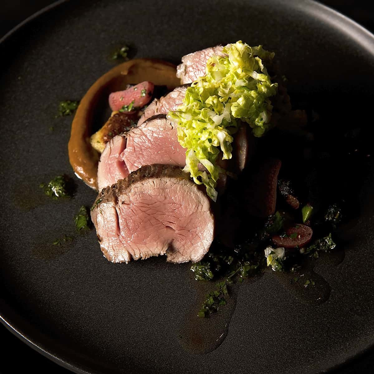 A black plate topped with meat and vegetables