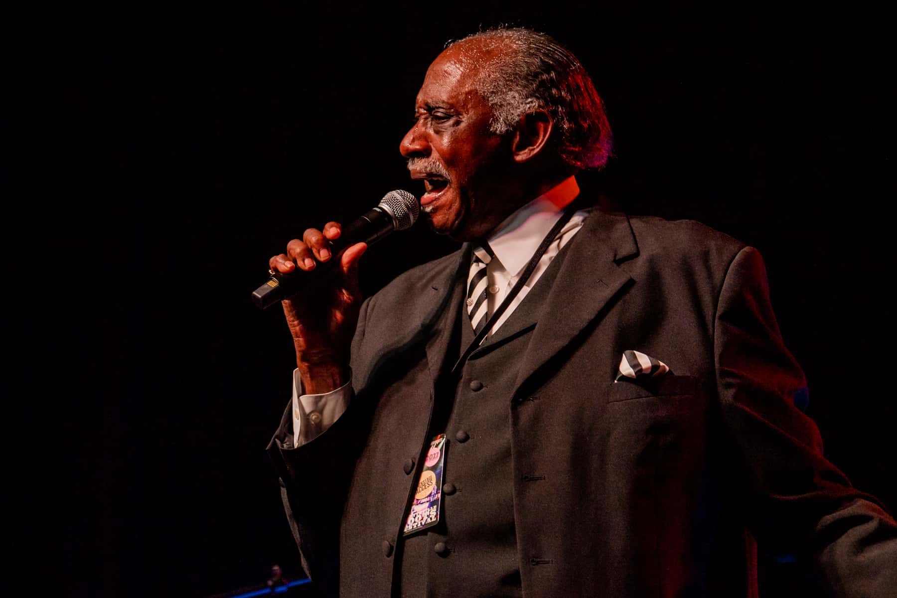 A man in a suit and tie is singing into a microphone.