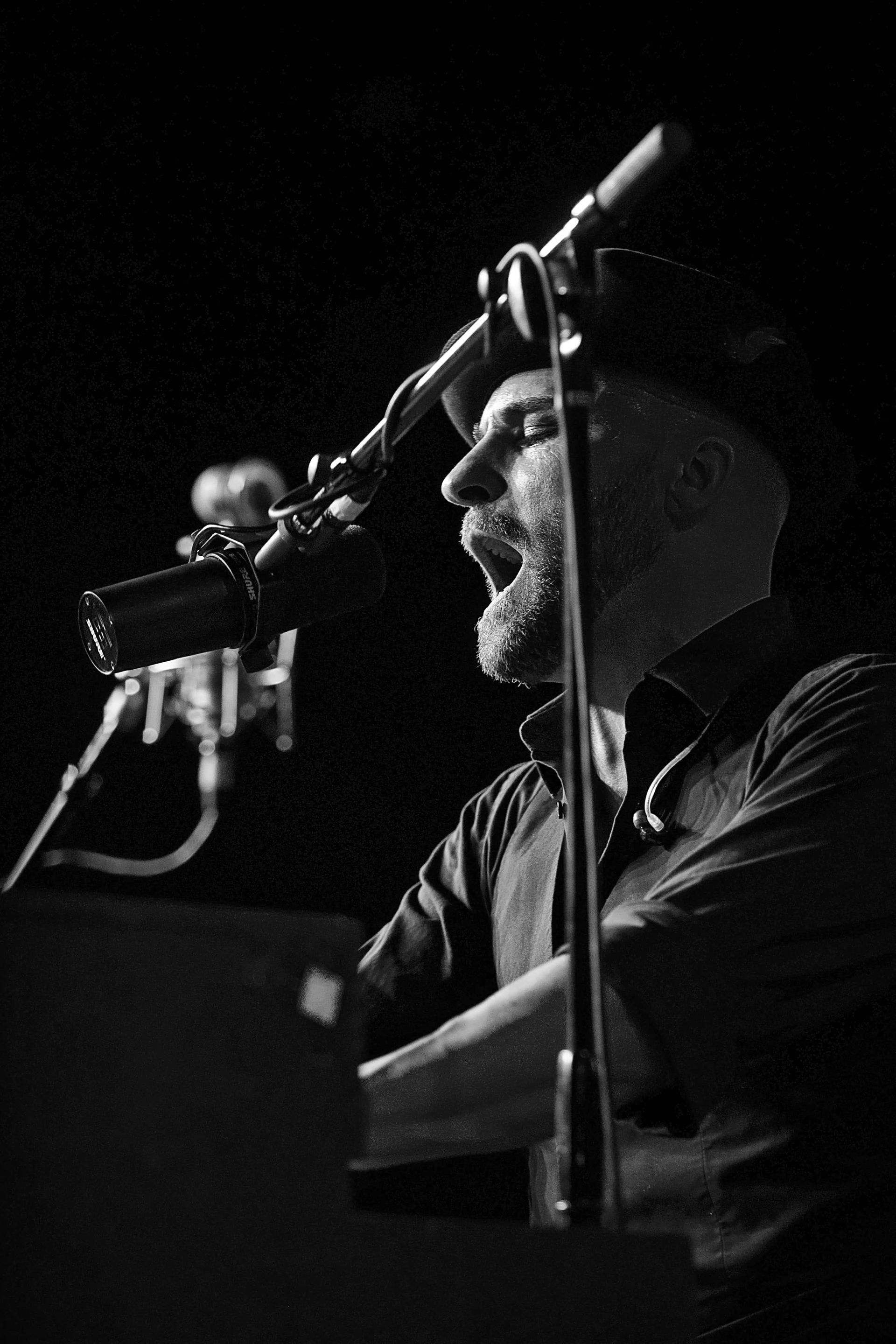 A man is singing into a microphone while holding a guitar.