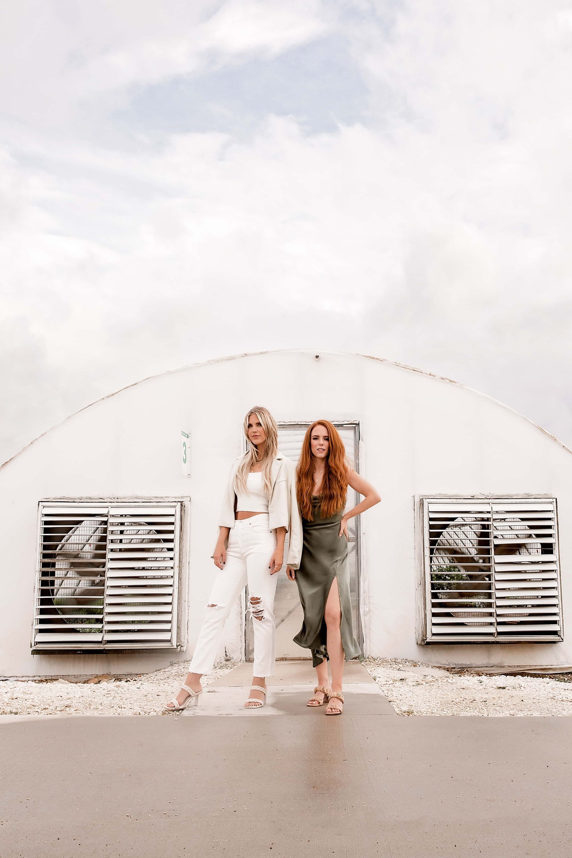 Two women are standing in front of a white building.