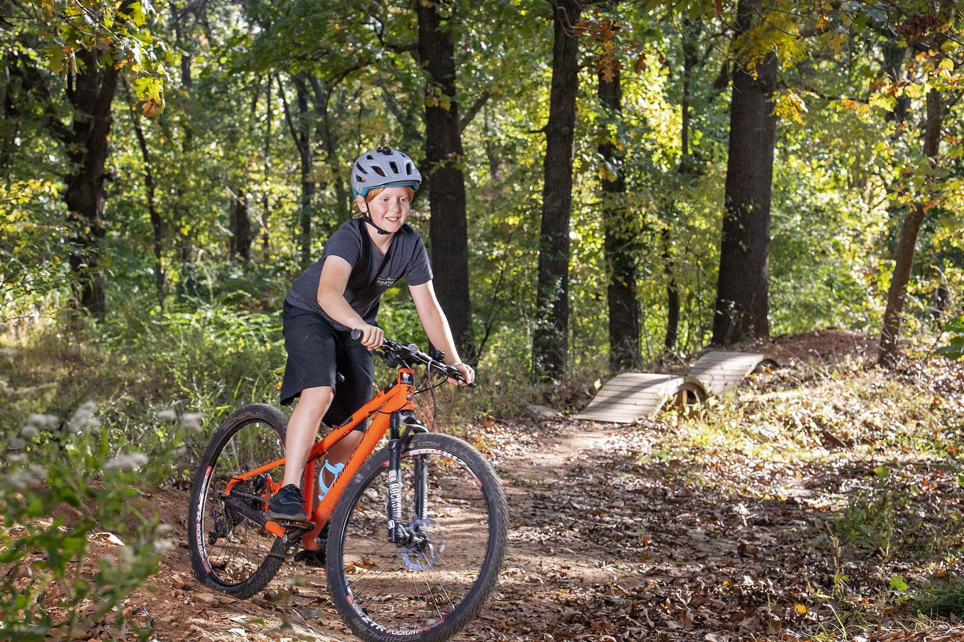 A young boy is riding a bike on a trail in the woods.