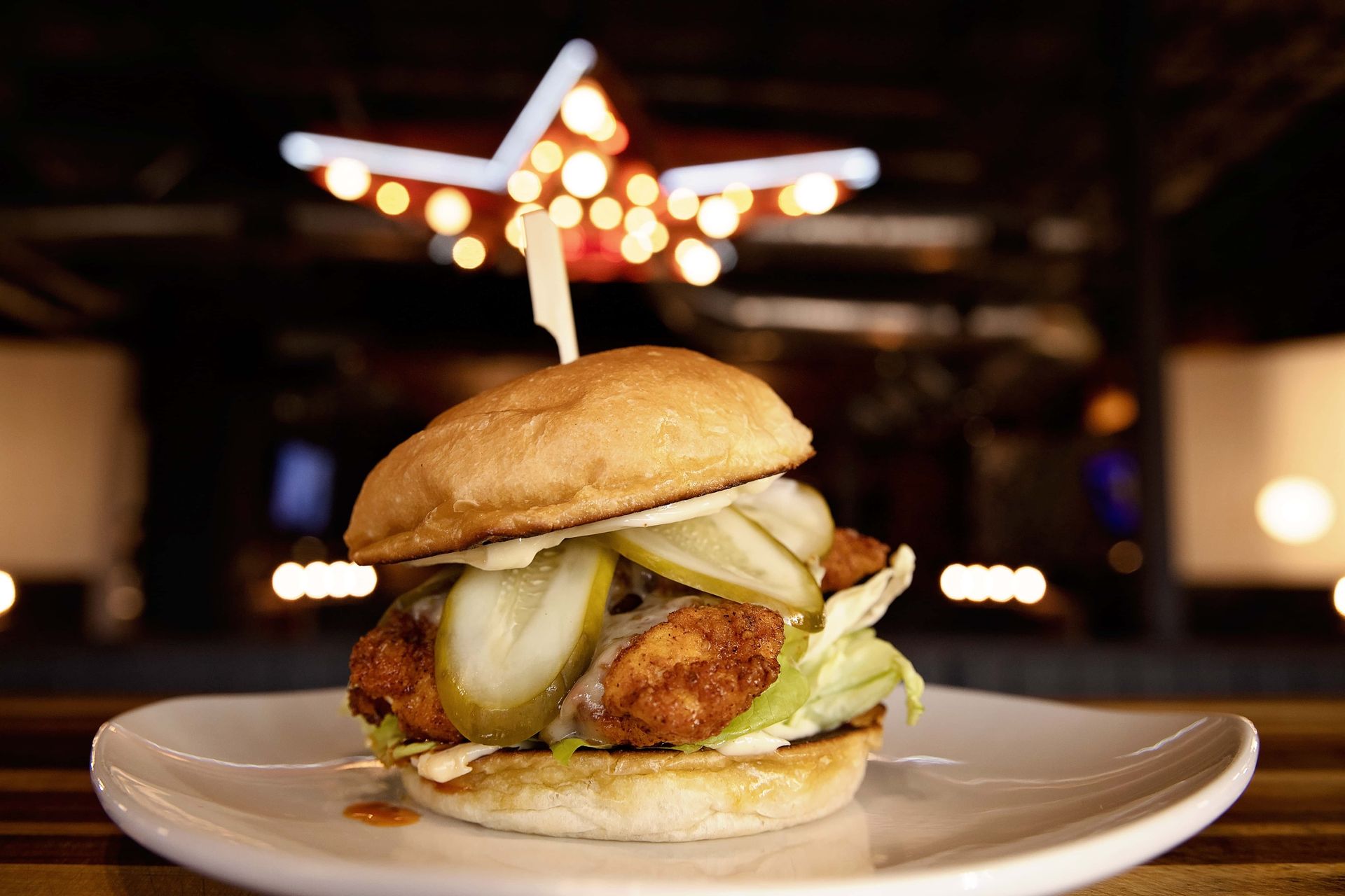 A fried chicken sandwich with pickles on a white plate