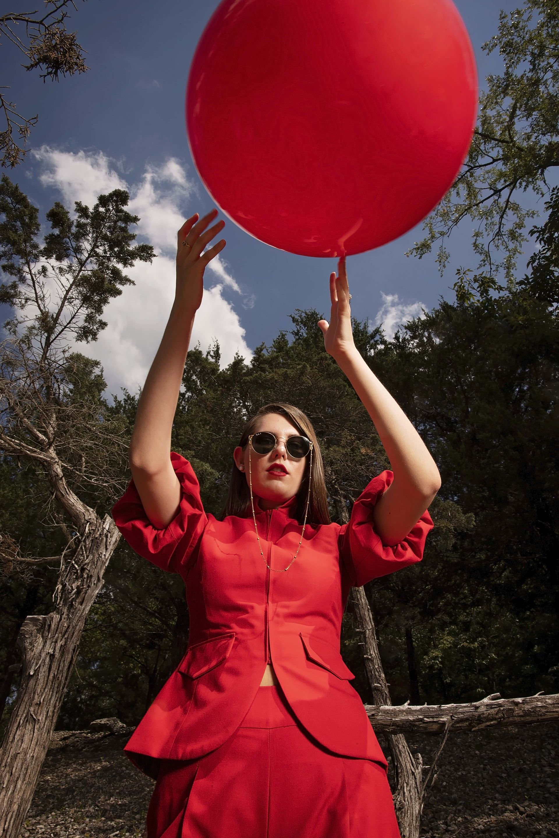 A woman in a red dress is holding a red balloon.