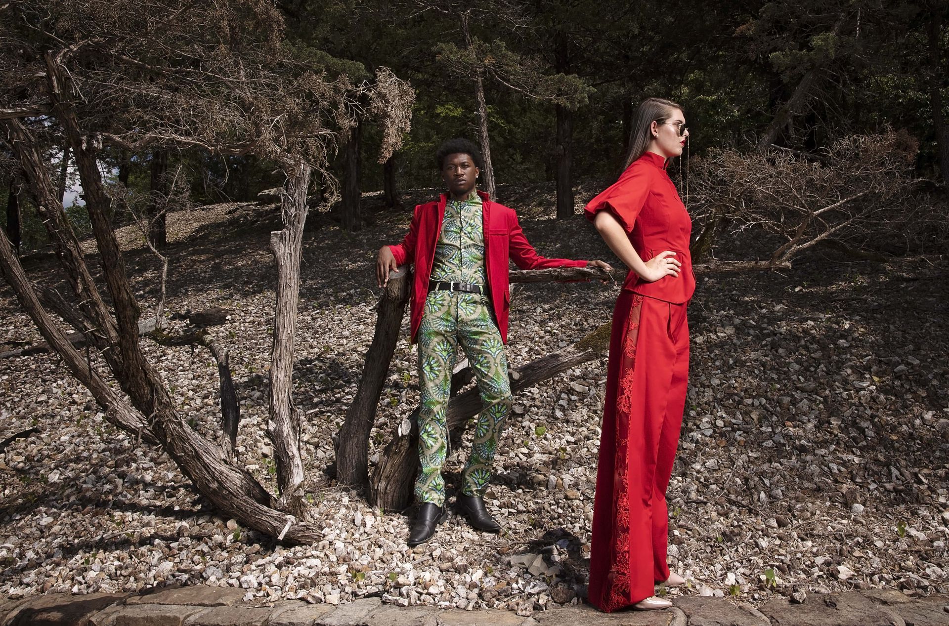 A man and a woman are standing next to each other in the woods.