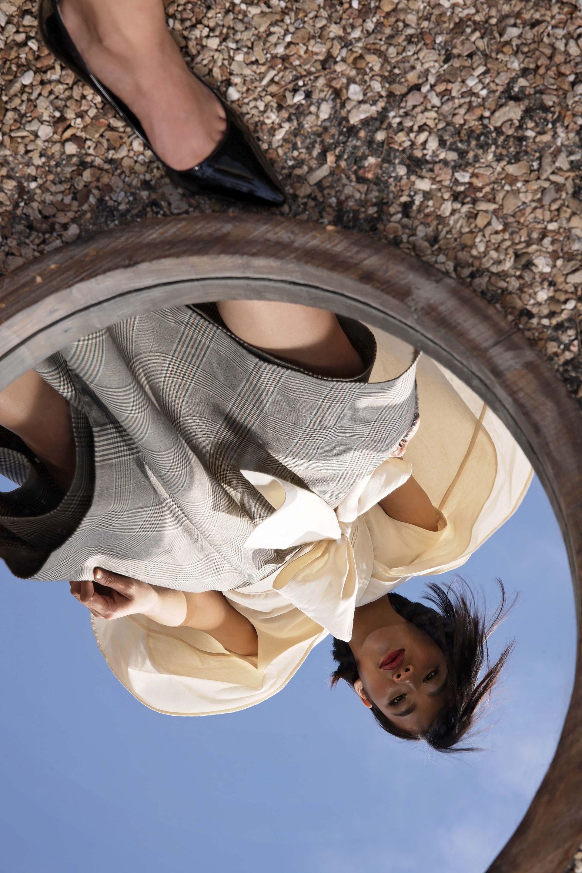 A woman is looking down at her reflection in a mirror.