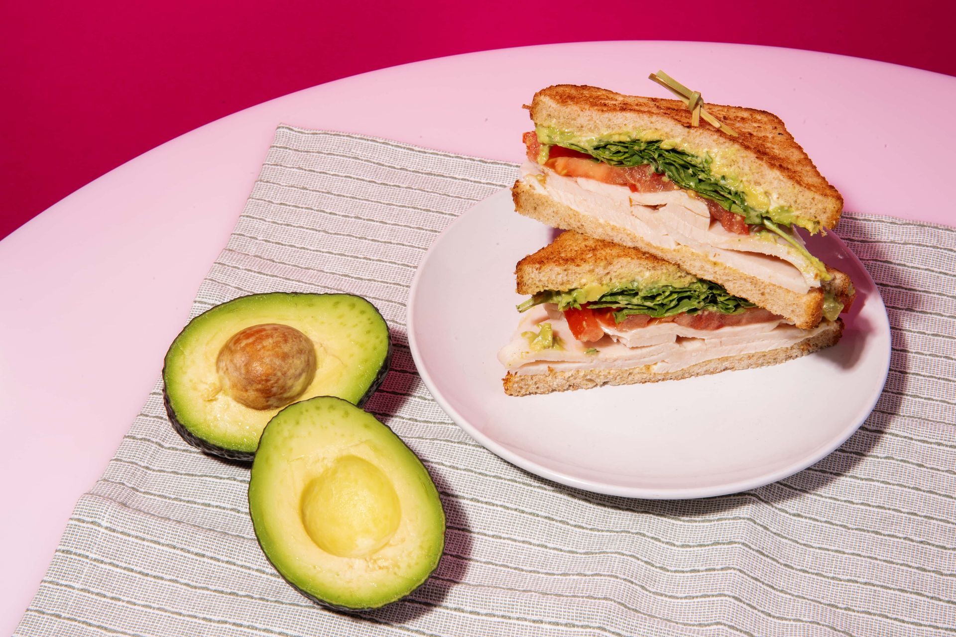 There is a sandwich on a plate with avocados next to it.