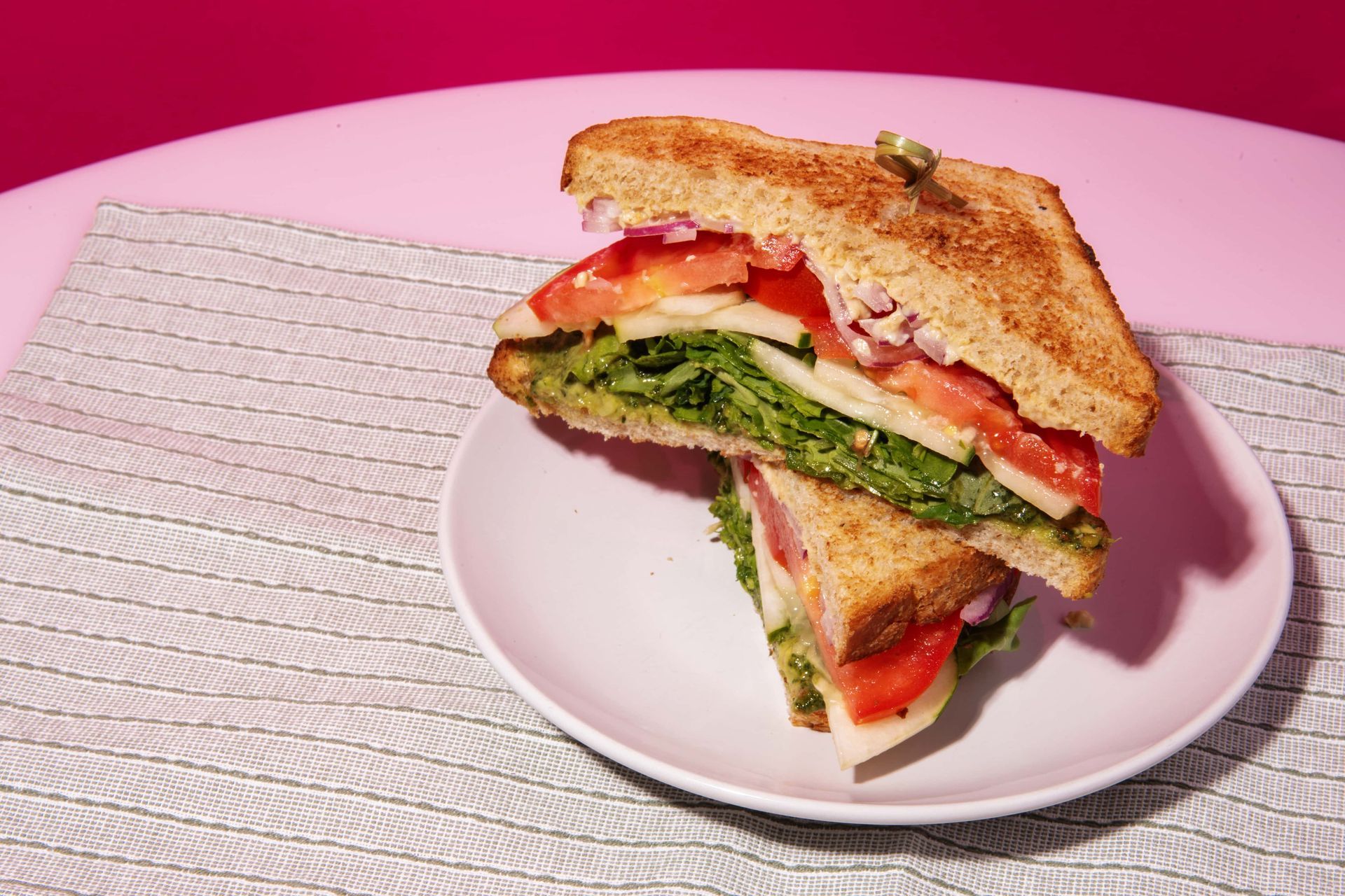 A sandwich is cut in half on a white plate on a table.