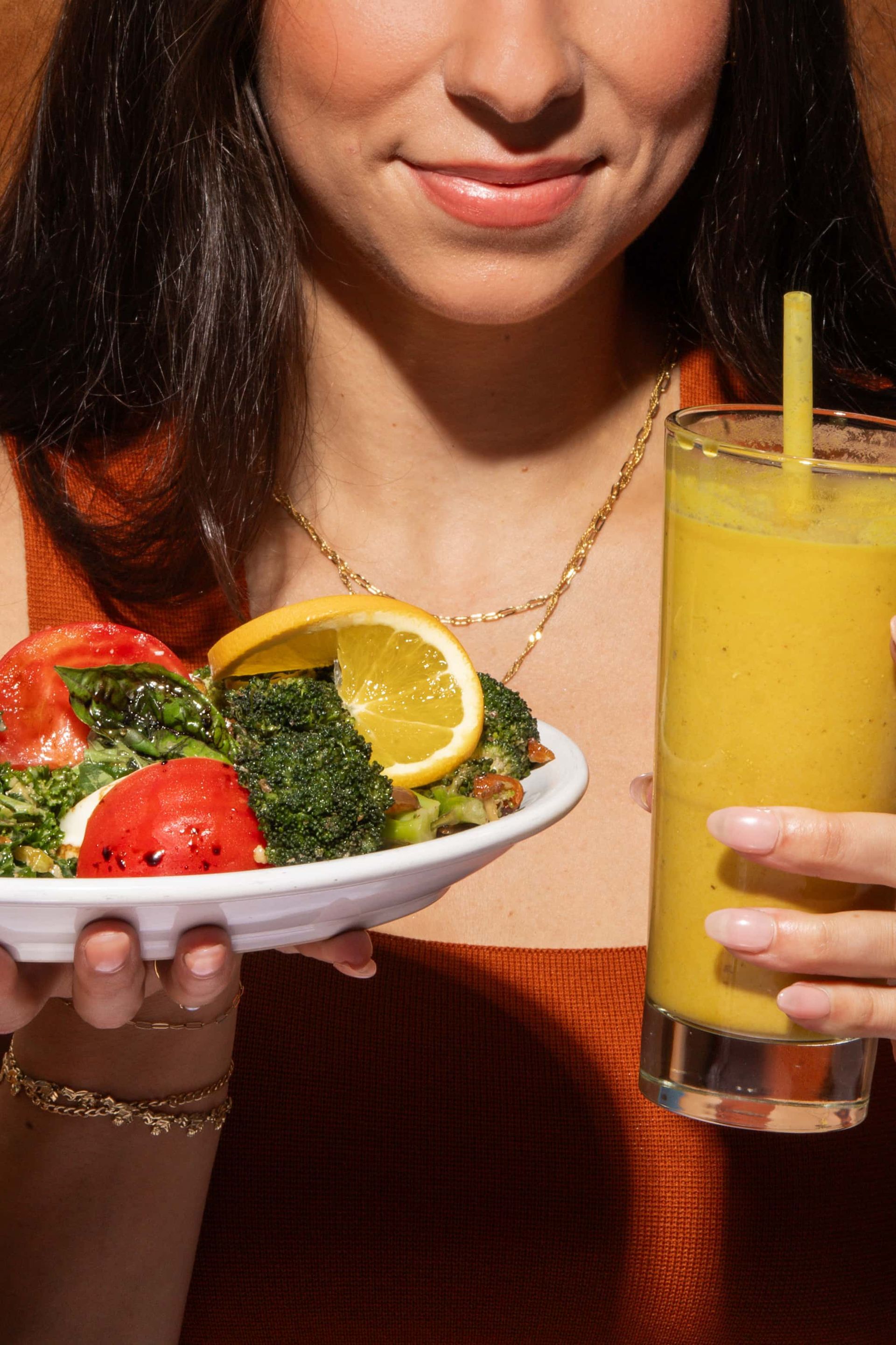 A woman is holding a plate of food and a glass of juice