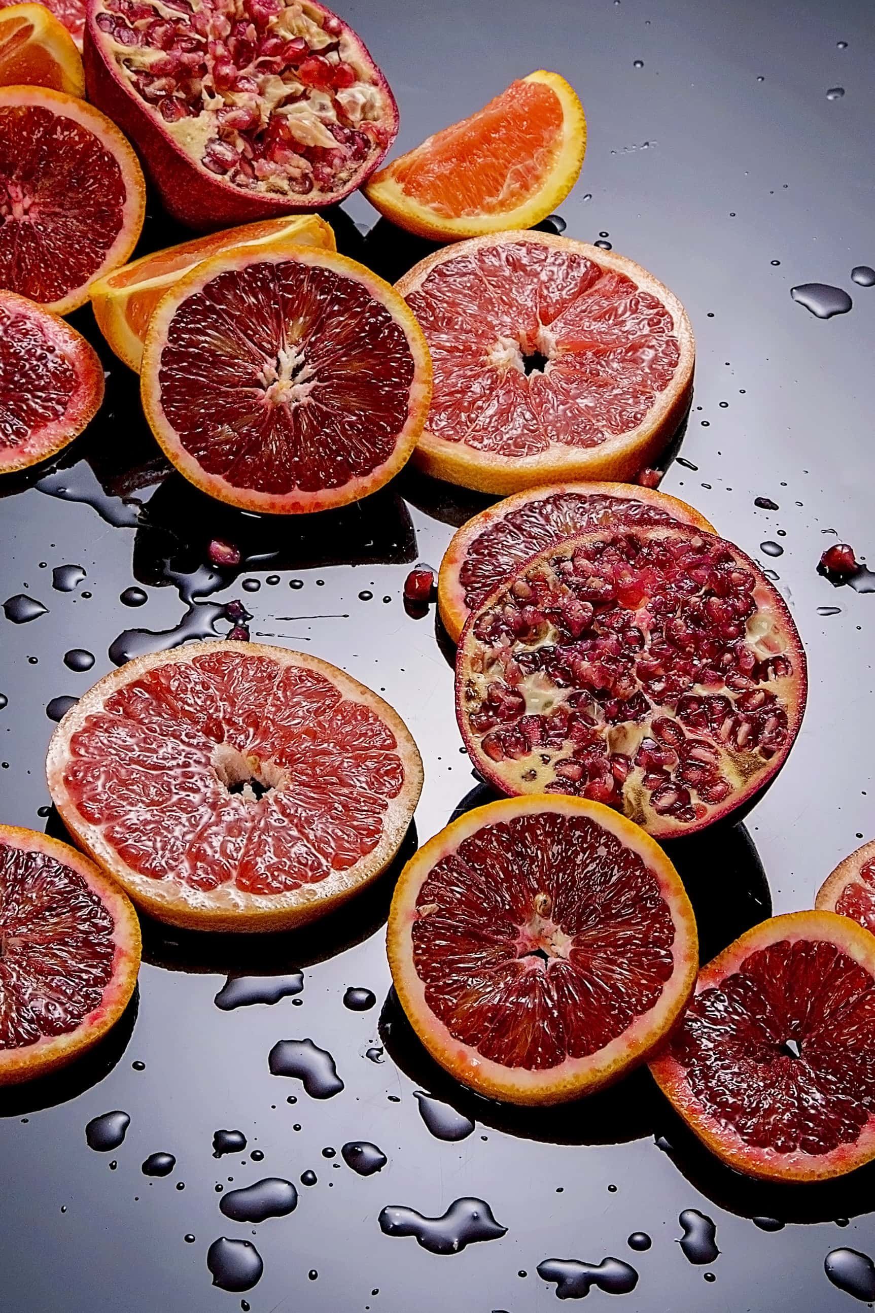 A bunch of grapefruit slices are sitting on a black surface.