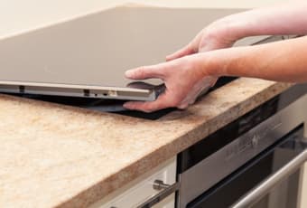 Persons hands removing a stove top from a counter.