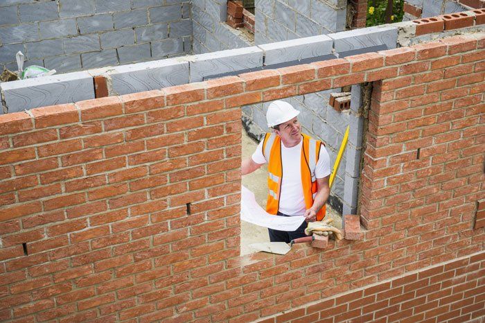 construction worker reading blueprint at brick wall