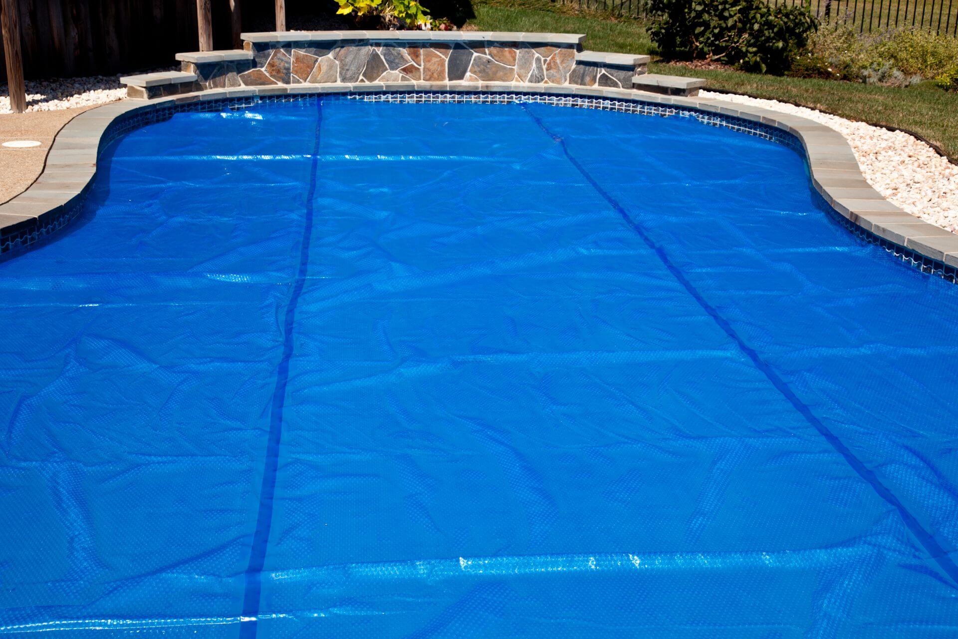 Blue pool covering placed on a custom shaped pool