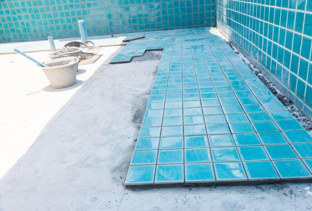 Blue tiles being installed in a pool under renovation