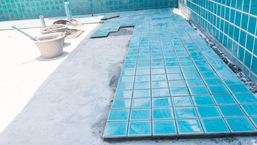 Blue tiles being installed in a pool under renovation