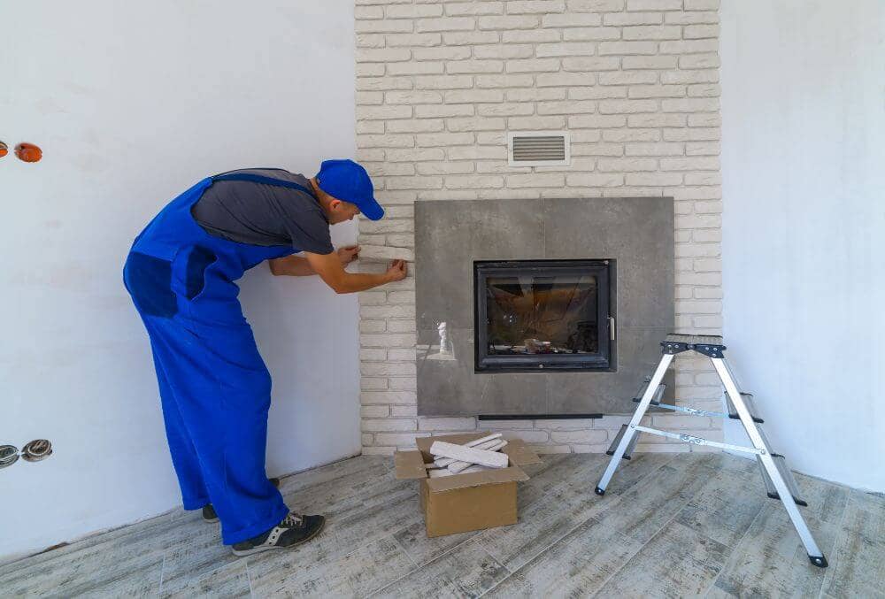 Contractor in blur jumpsuit installing final touches for a fireplace
