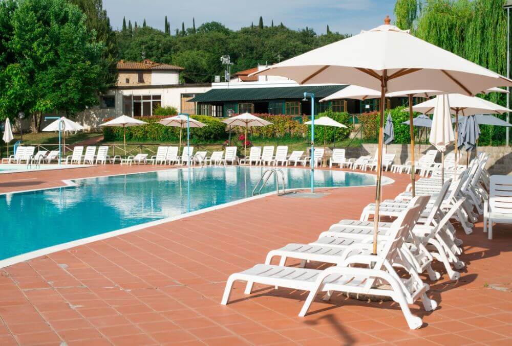 Custom shaped pool with white beach chairs surrounding it