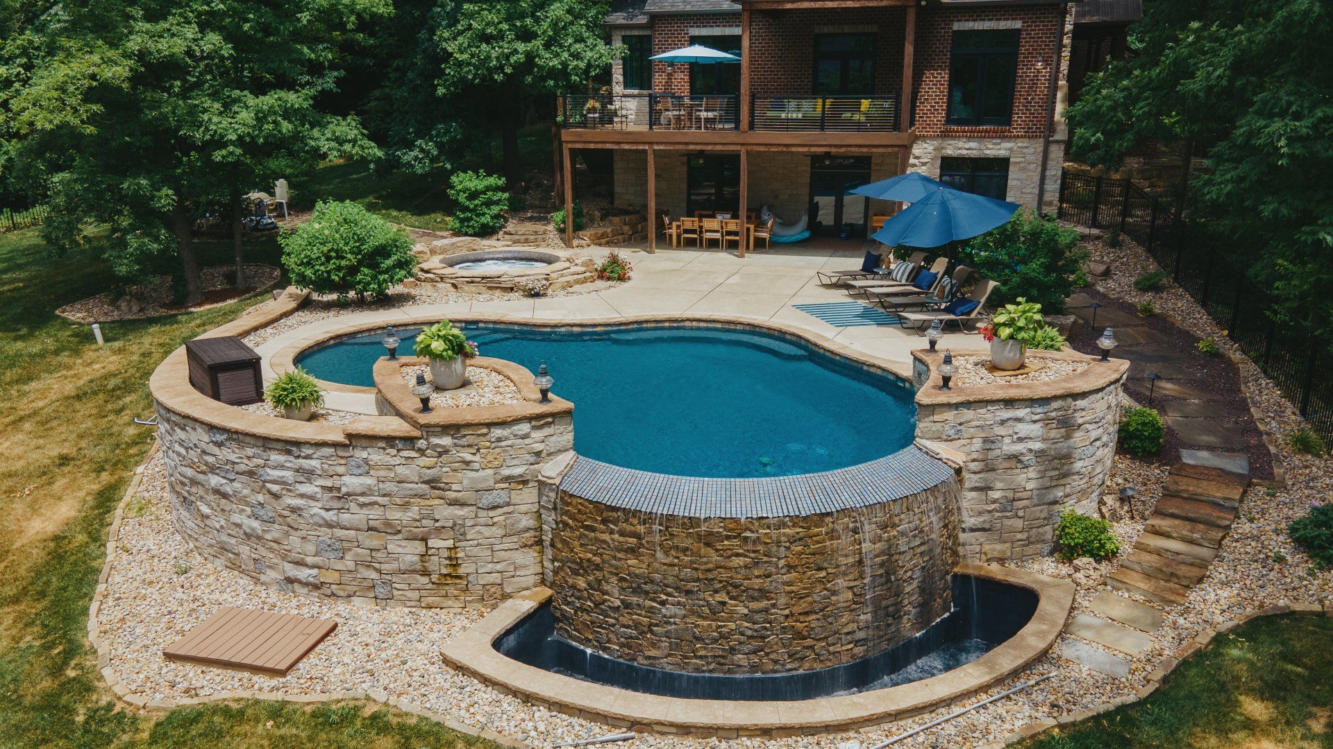 Custom form pool with rock waterfalls feature in front of a desert themed house.jpg