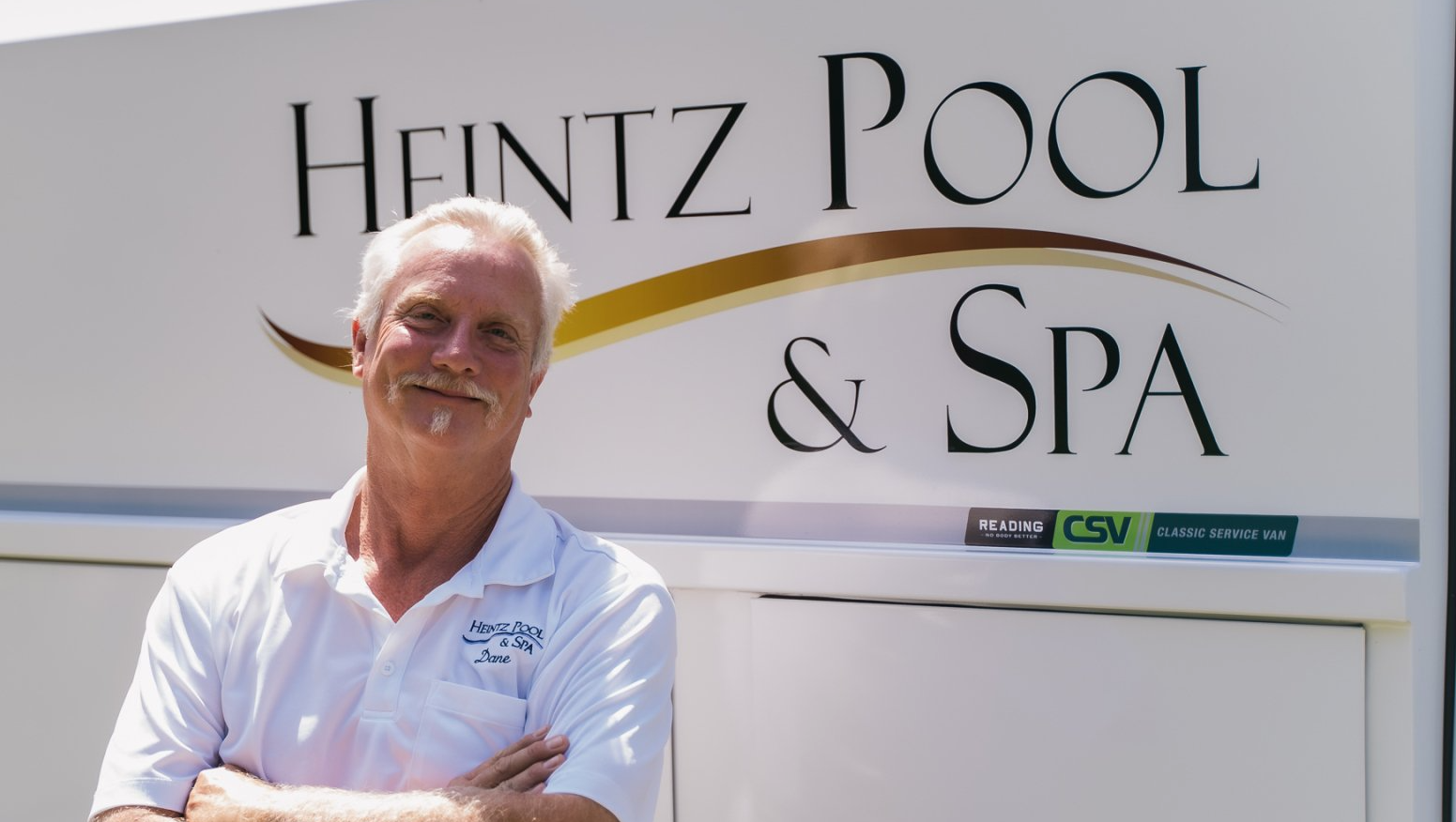 Heintz Pool & Spa employee in white shirt standing beside company car