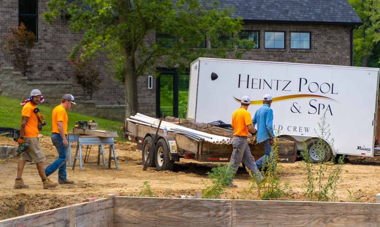 Team of pool and spa builder walking beside a pool under construction