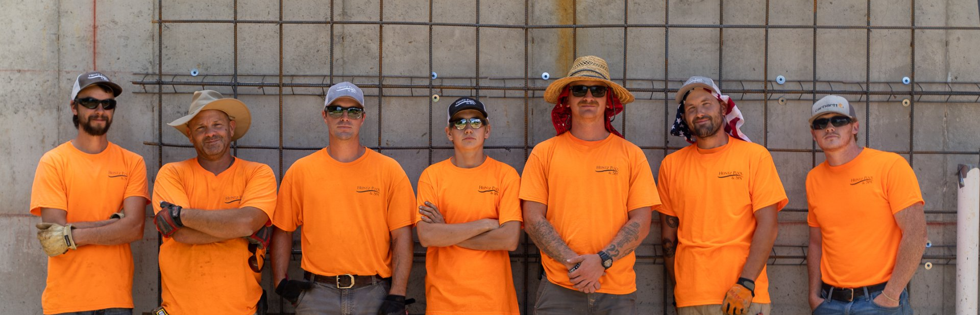 Seven members of Heintz Pool & Spa team wearing their orange uniform standing side by side