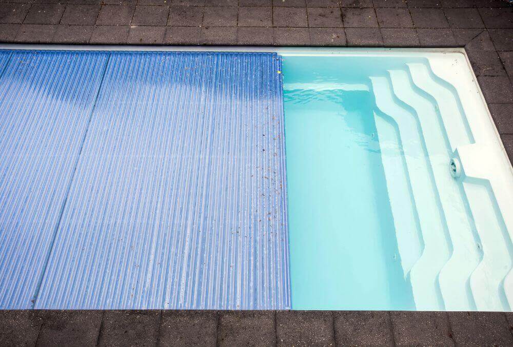 Pool cover being slided to prepare for spring uncovering crystal clear water