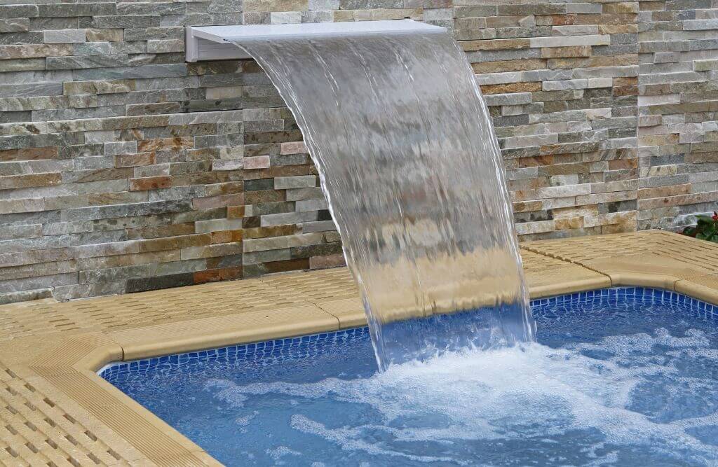 Sheer  waterfall feature operating from the side of a swimming pool