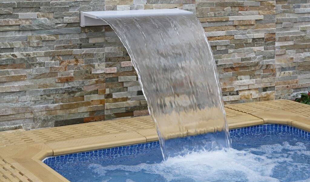 Sheer waterfall feature operating from the side of a swimming pool