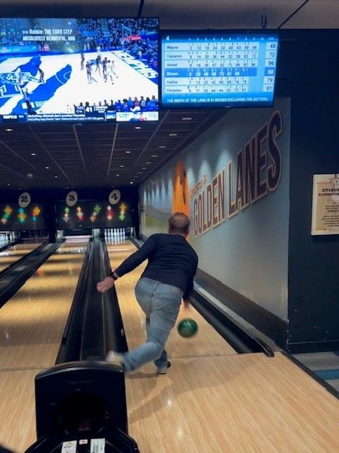 a man is throwing a bowling ball in a bowling alley with the words golden lanes on the wall