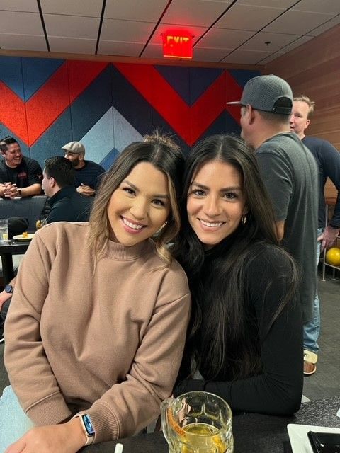 two women are posing for a picture in a bowling alley