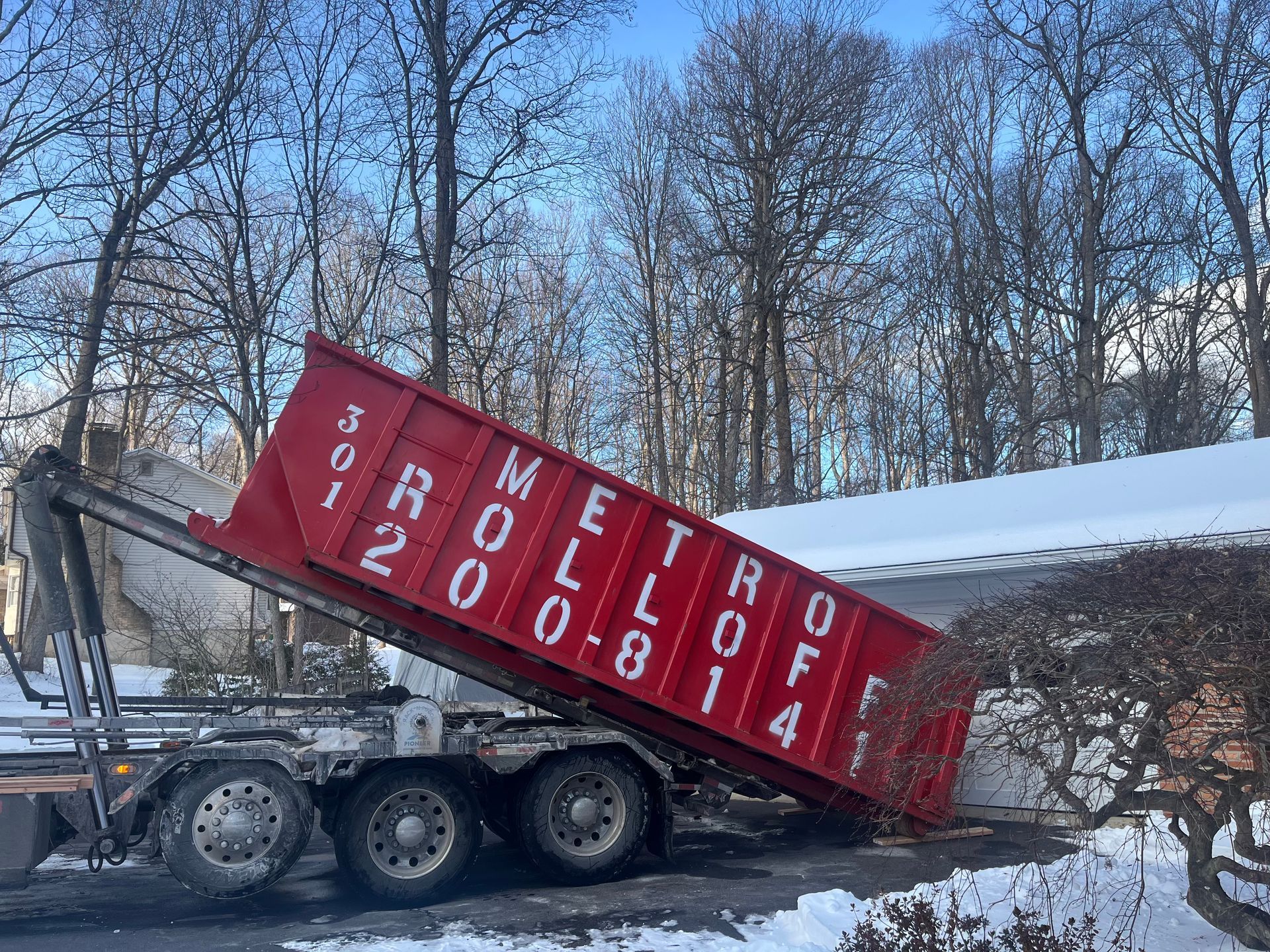 Blue dumpster with wheels, side panel with hinges and latch, set against a brick building.