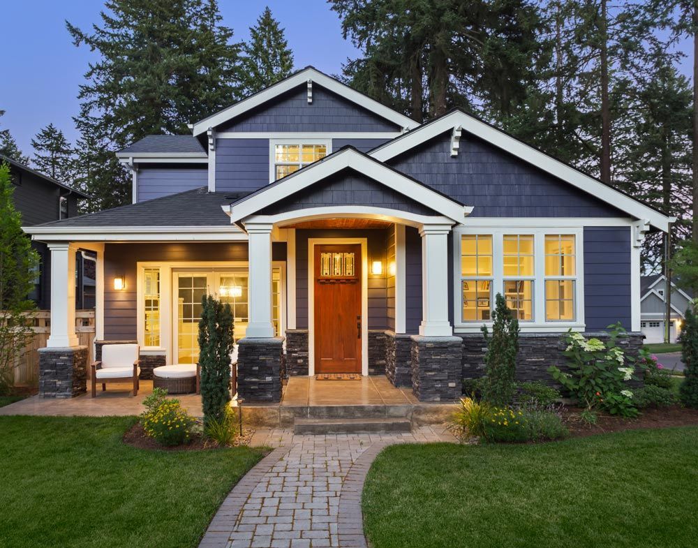 A blue and white house with a brick walkway leading to it