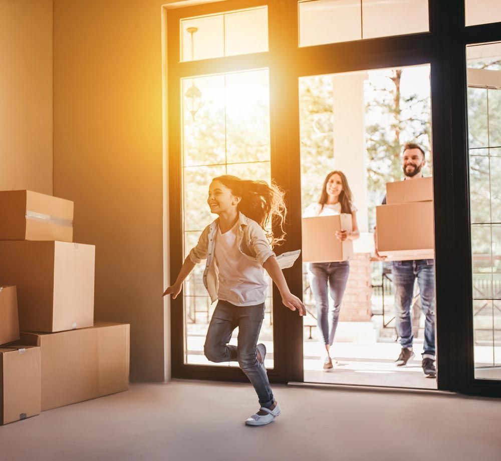 A family is moving into a new home and carrying boxes.