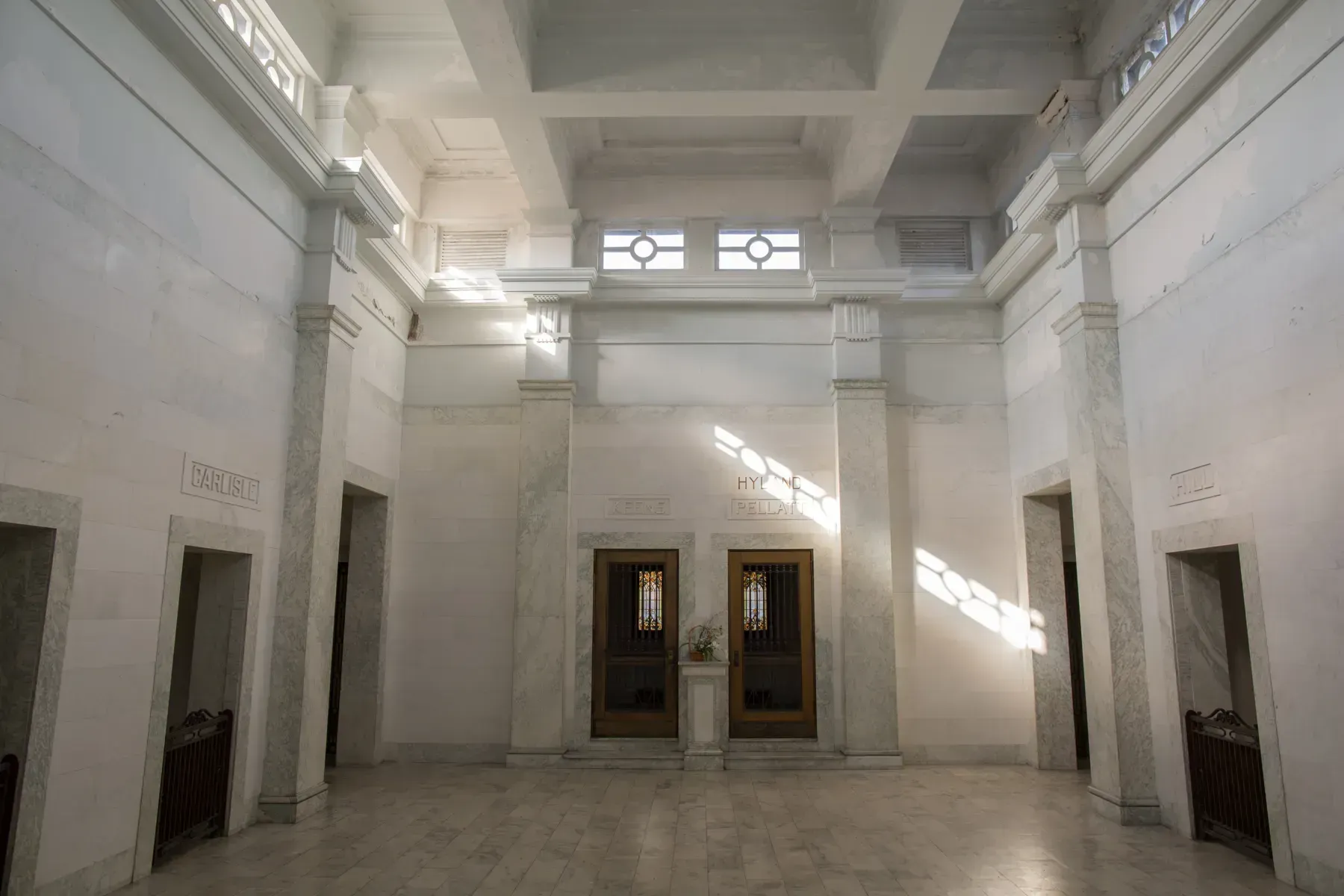 Empty white marble lobby with high ceiling and bright sunlight through upper windows