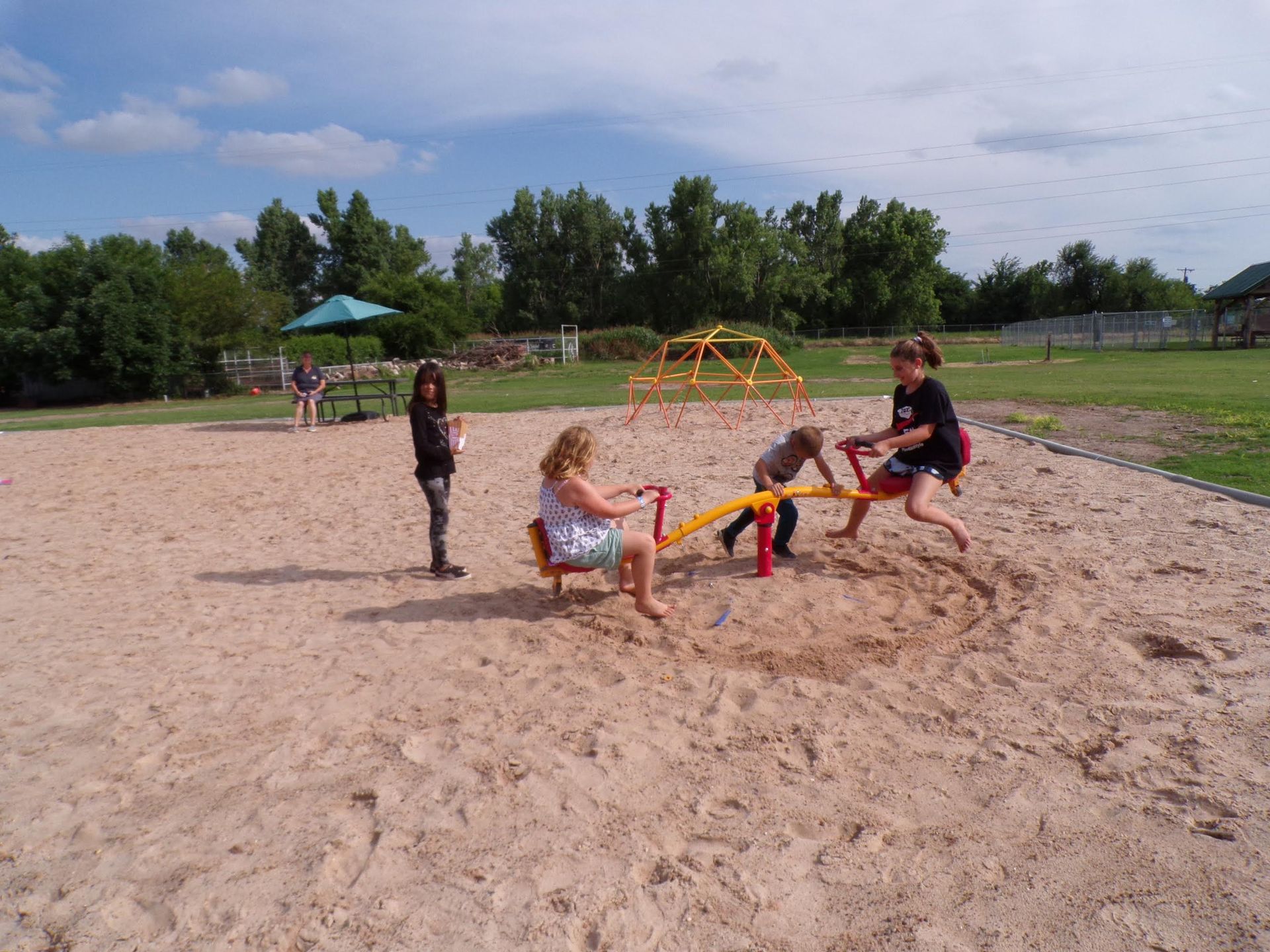 A group of children are playing on a seesaw in the sand.