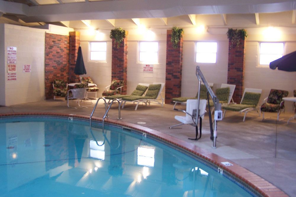 An indoor swimming pool with chairs and umbrellas around it