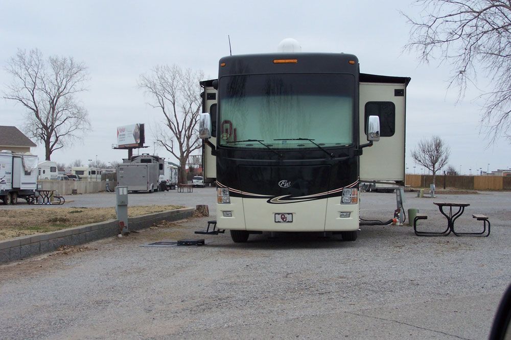 A large rv is parked in a parking lot next to a picnic table