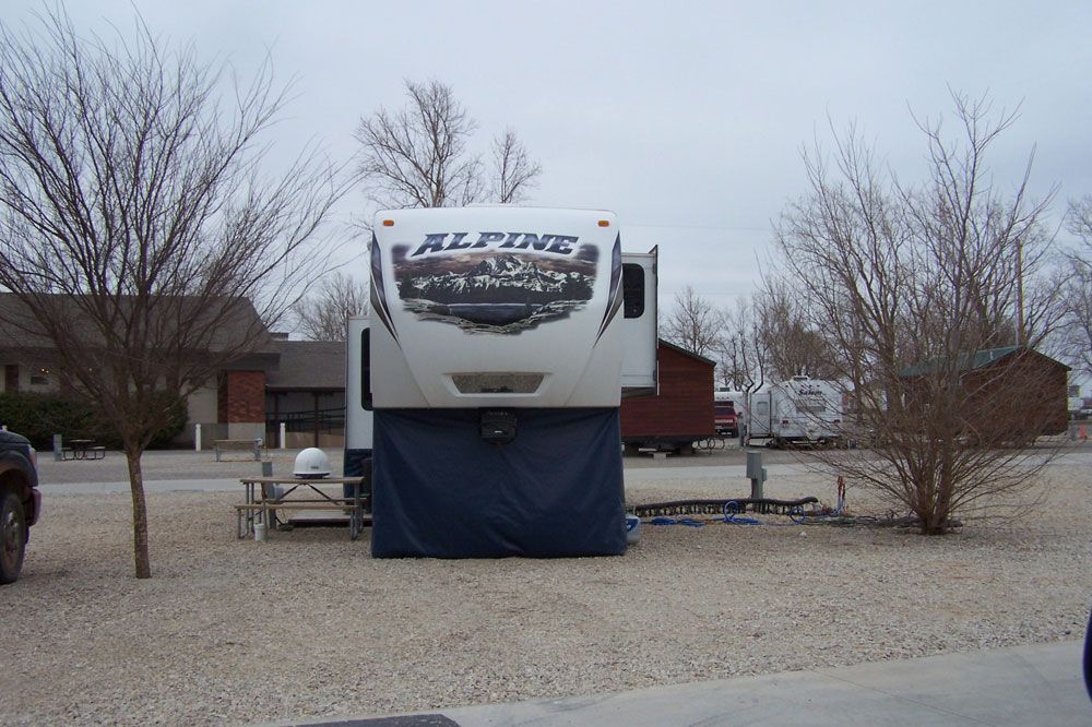 An alpine rv is parked in a gravel lot