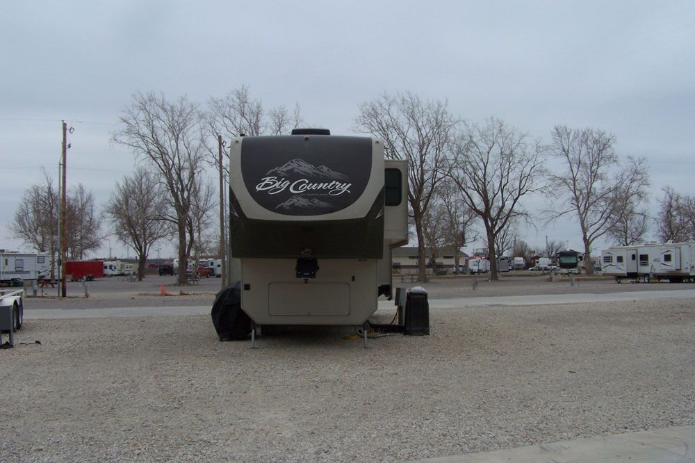 A rv parked in a gravel lot with trees in the background