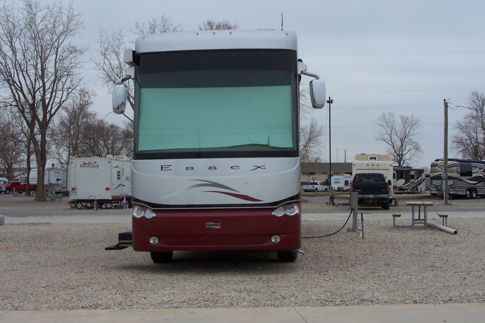 A large red and white rv is parked in a gravel lot