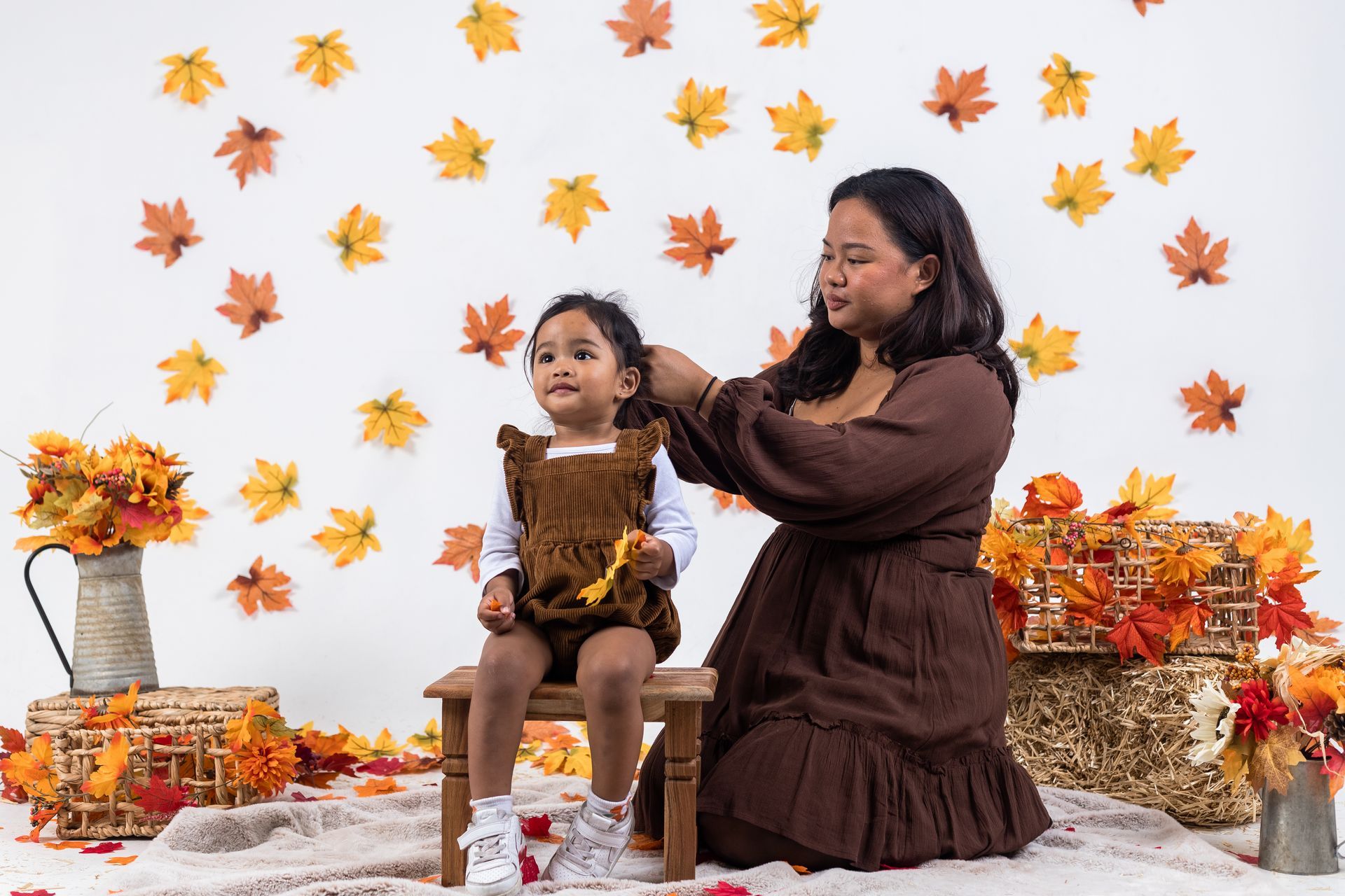 a woman is brushing a little girl 's hair while sitting on a stool .