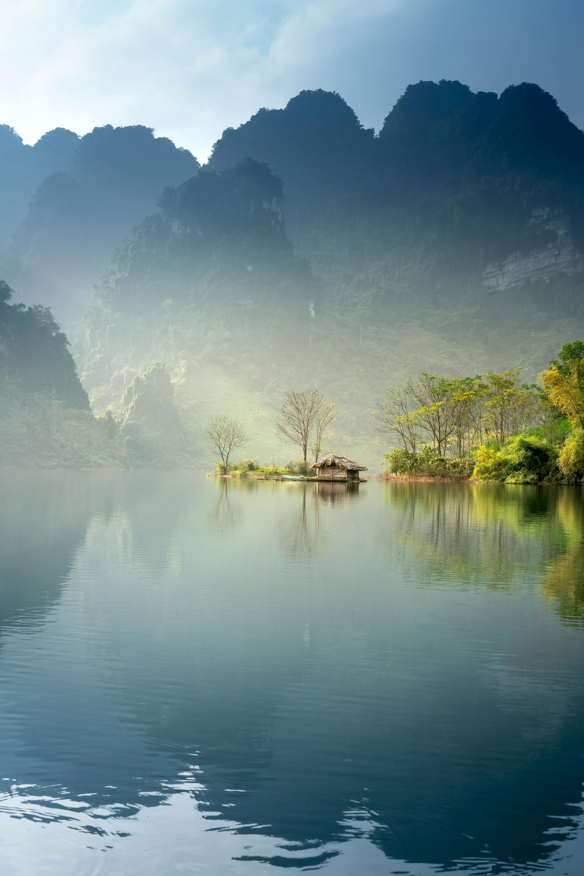A small island in the middle of a lake with mountains in the background.
