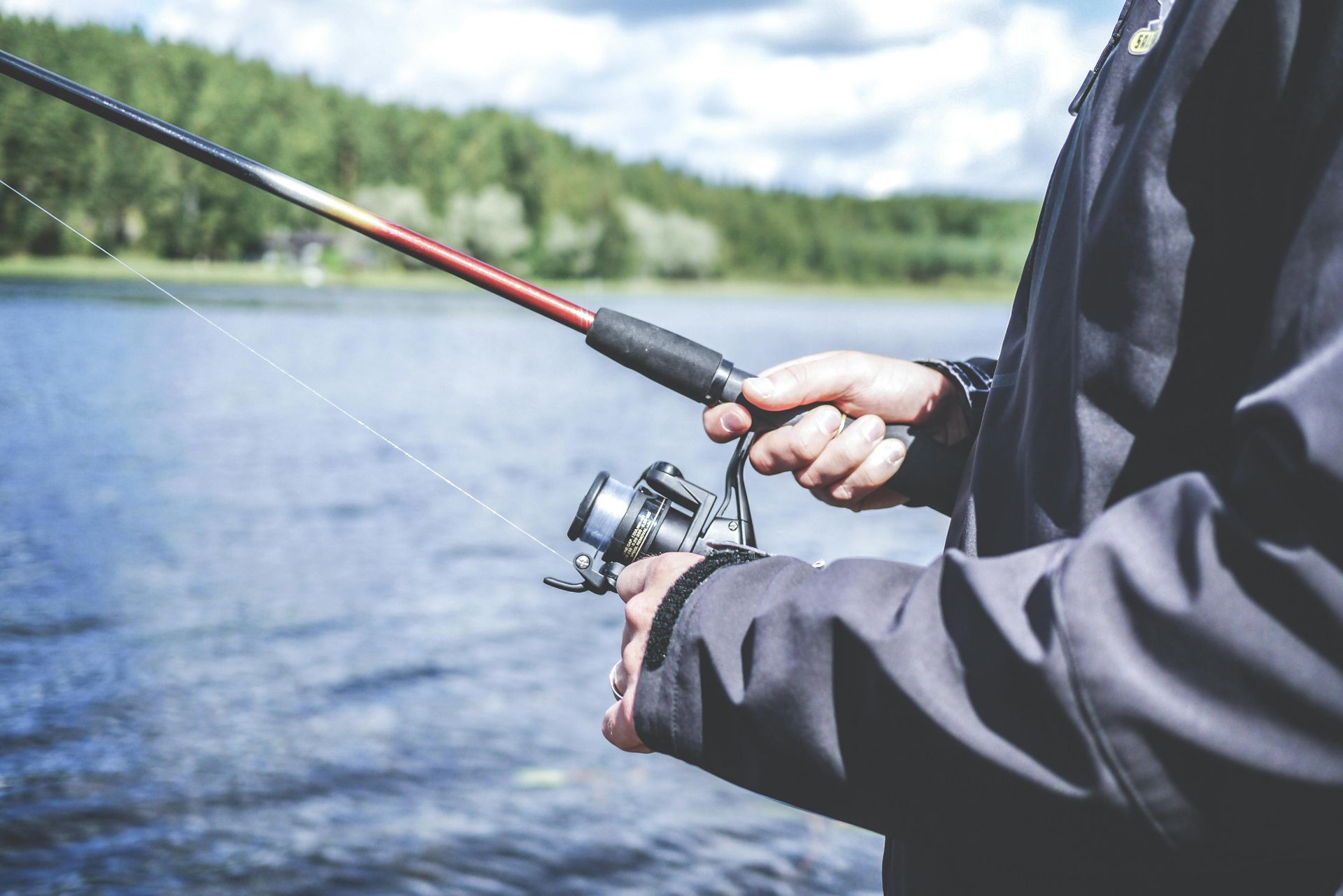 A man is fishing on a lake with a fishing rod.