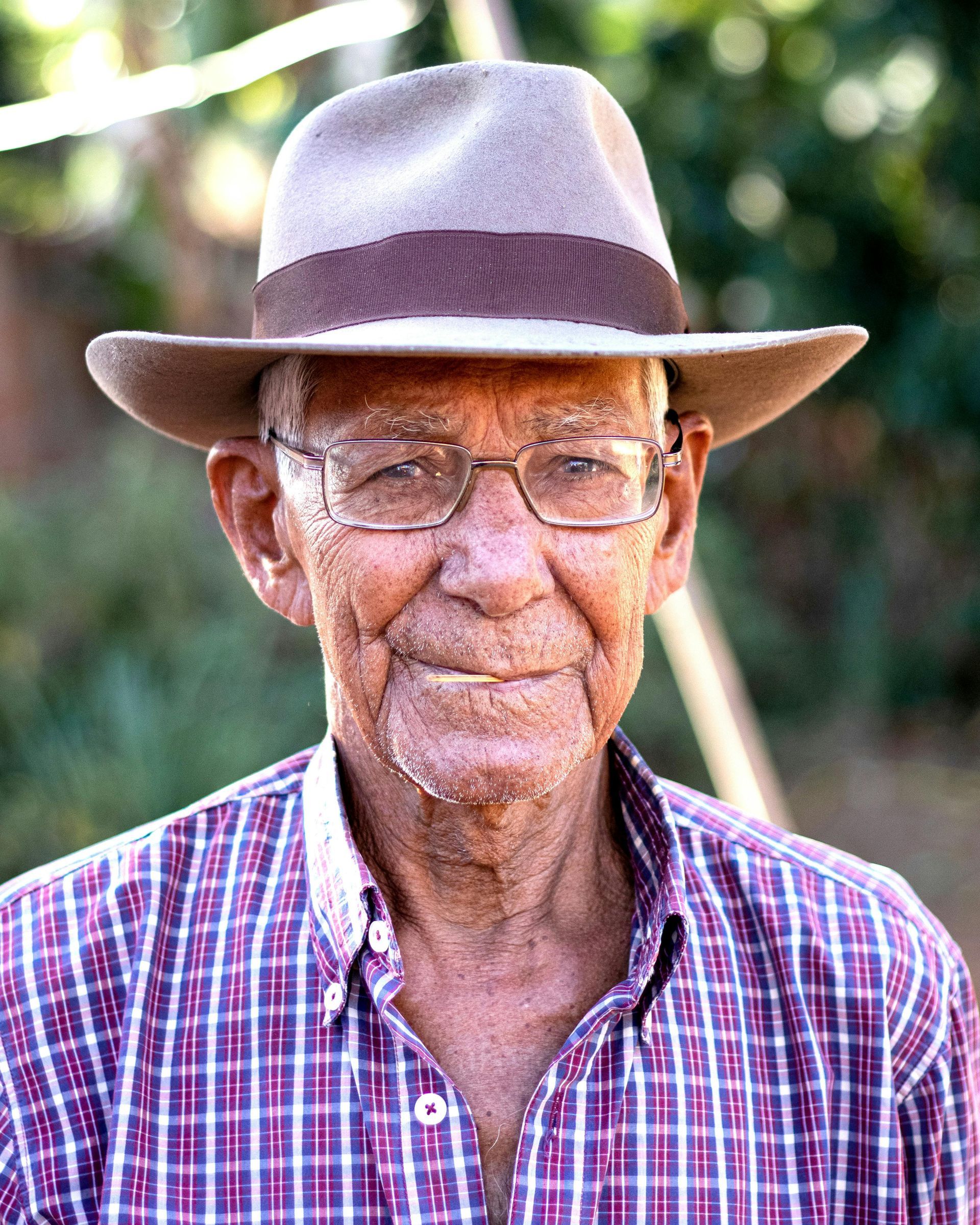 A man wearing a hat and glasses is smiling for the camera.
