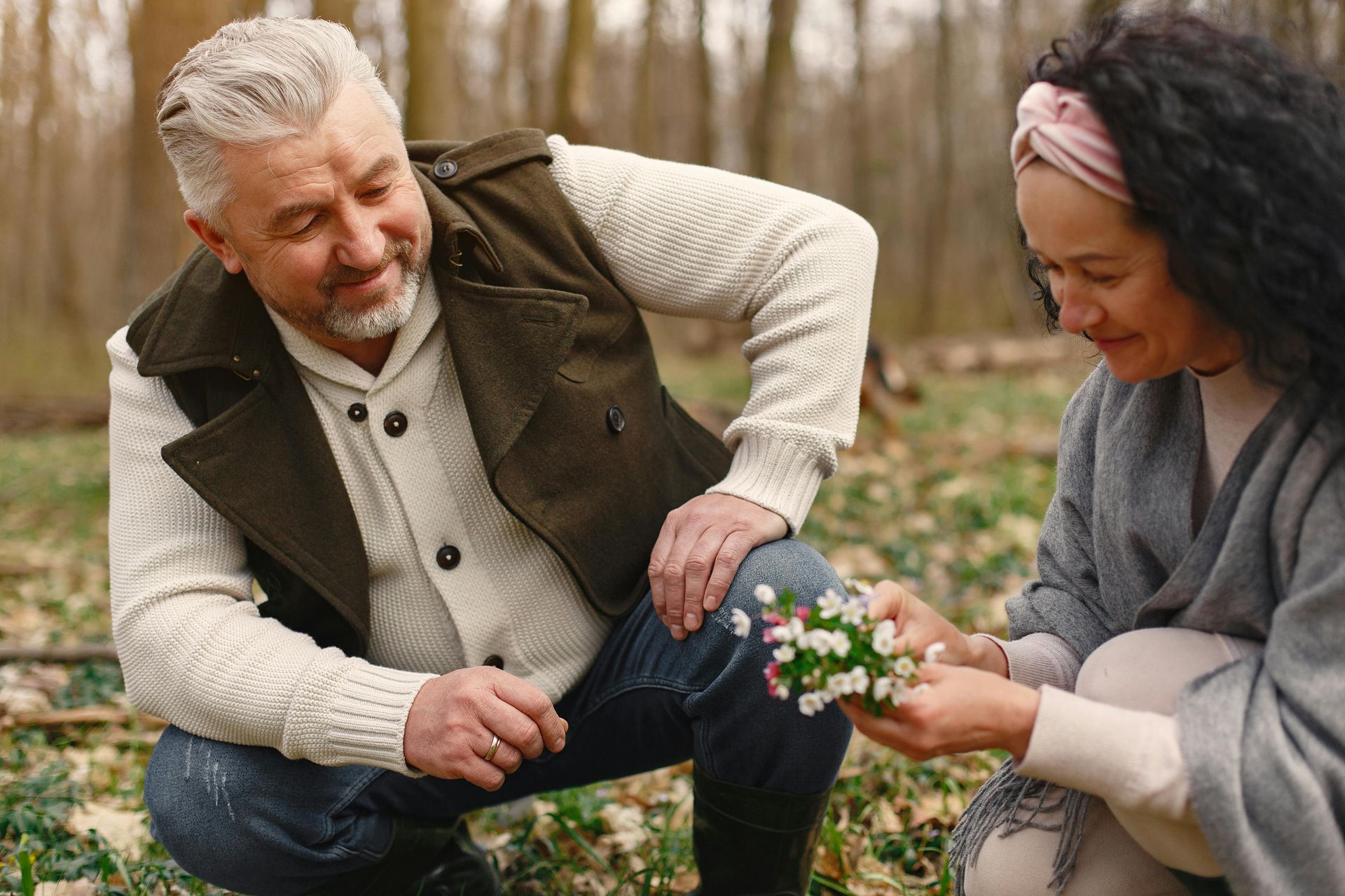 A woman is giving a flower to a man in the woods.