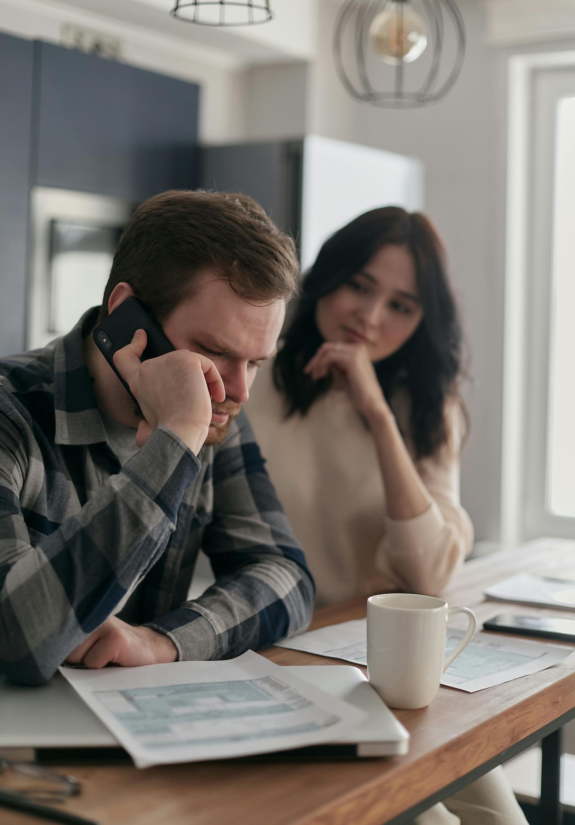 A man is talking on a cell phone while sitting at a table with a woman.