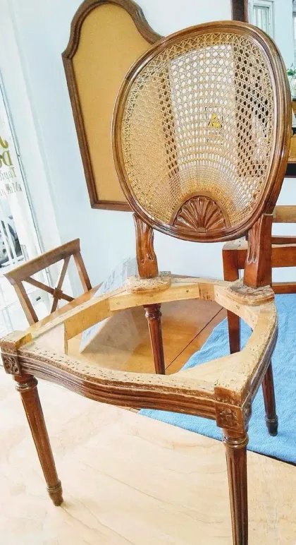Silla de mimbre tejido con estructura de madera y tapicería color canela en una habitación luminosa.